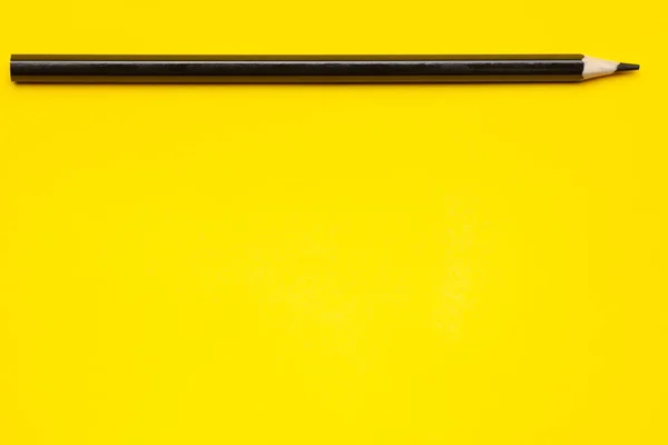 Horizontal black sharp wooden pencil on a bright yellow background, isolated, copy space, mock up — Stock Photo, Image