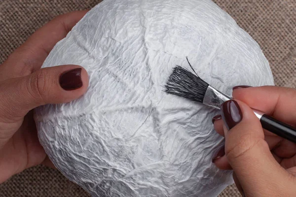 The process of creating a pumpkin from papier-mache, applying glue to the base , a hobby for Halloween decorations — Stock Photo, Image