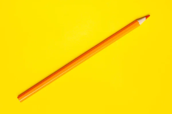Diagonal orangefarbener scharfer Holzstift auf leuchtend gelbem Hintergrund, isoliert, Kopierraum, Attrappe — Stockfoto