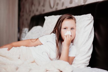 Bir çocuk kravat üzerine yatar ve sümüğü peçetelerle siler. Covid-19 virüsünün ikinci dalgası.