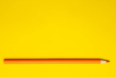 parlak sarı bir zemin üzerinde yatay turuncu keskin tahta kalem, izole edilmiş, kopyalama alanı, taklit