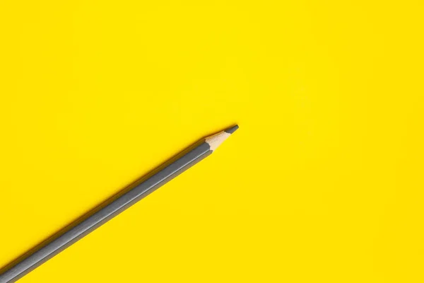 Diagonal gray sharp wooden pencil on a bright yellow background, isolated, copy space, mock up — Stock Photo, Image