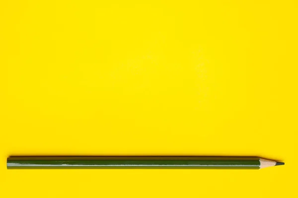 Crayon en bois pointu vert foncé horizontal sur un fond jaune vif, isolé, espace de copie, maquette — Photo