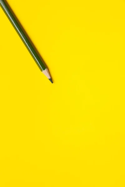 Crayon en bois pointu vert foncé en diagonale sur fond jaune vif, isolé, espace de copie, maquette — Photo
