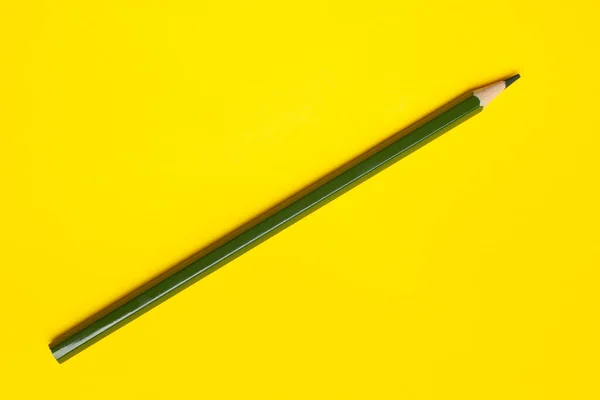 Діагональний темно-зелений гострий дерев'яний олівець на яскраво-жовтому тлі, ізольований, простір для копіювання, сміється — стокове фото