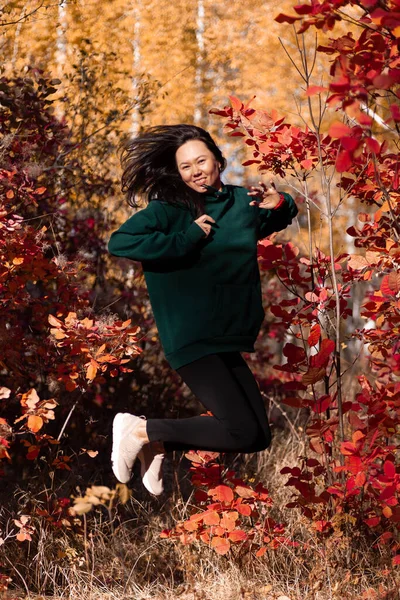 Pełnowymiarowy portret pięknej Azjatki skaczącej w jesiennym lesie o zachodzie słońca — Zdjęcie stockowe