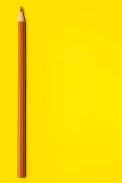 Vertical light brown sharp wooden pencil on a bright yellow background, isolated, copy space, mock up — Stock Photo, Image