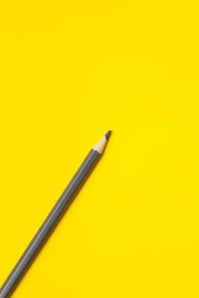 Diagonal gray sharp wooden pencil on a bright yellow background, isolated, copy space, mock up — Stock Photo, Image