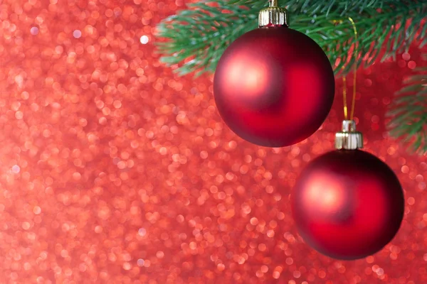 Dos bola brillante rojo en una rama de árbol de año nuevo sobre un fondo borroso rojo, se burlan de — Foto de Stock