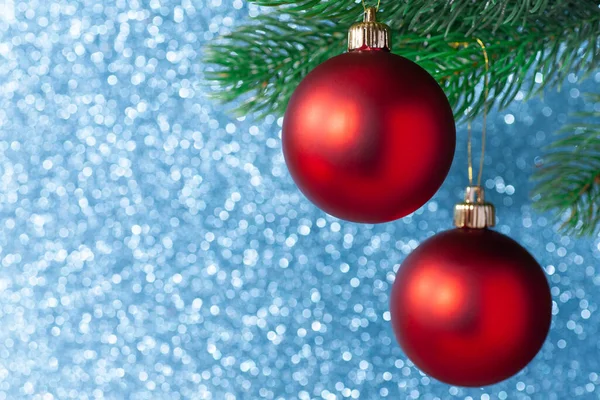 Dos bola brillante rojo en una rama de árbol de año nuevo sobre un fondo borroso azul, se burlan de — Foto de Stock
