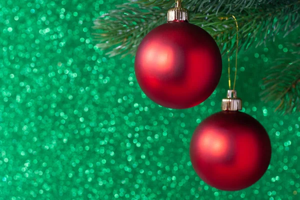 Dos bola brillante rojo en una rama de árbol de año nuevo sobre un fondo borroso verde, se burlan de — Foto de Stock