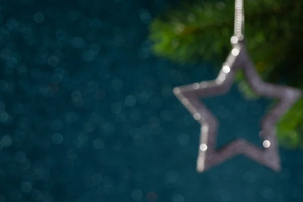 Fondo borroso de una rama de árbol de Navidad y una estrella de plata — Foto de Stock