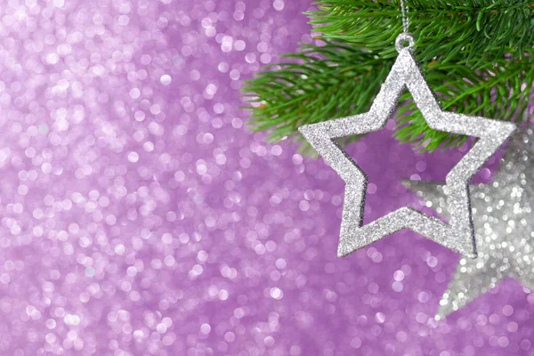 ピンク色から紫色に輝く背景のクリスマスツリーの枝に銀の星が2つ — ストック写真