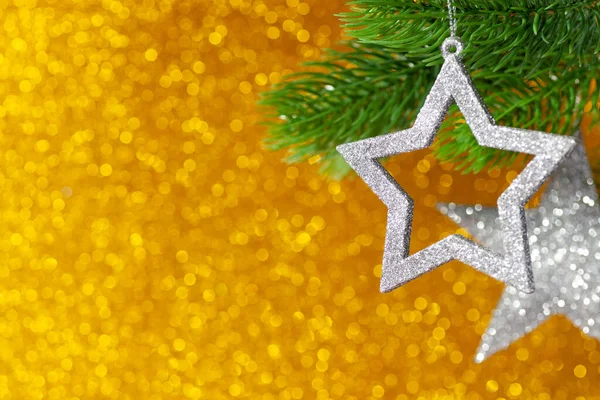 Dos estrellas de plata en una rama de árbol de Navidad sobre un fondo amarillo brillante de bokeh, se burlan de — Foto de Stock