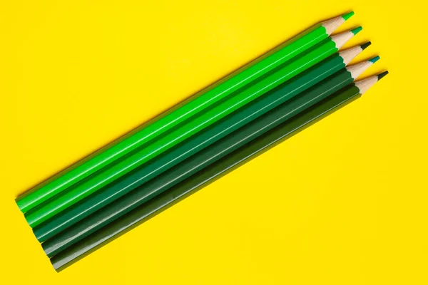 Lápices de madera afilados verdes diagonales sobre un fondo amarillo brillante, aislado, espacio de copia, se burlan de — Foto de Stock