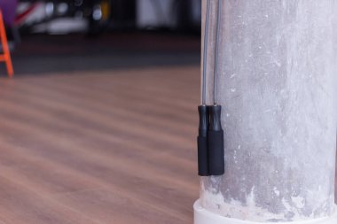 Spor salonundaki gri beton duvarda asılı ip atlama.