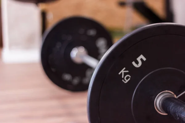 Olympic gym bar with black weight disc on parquet floor