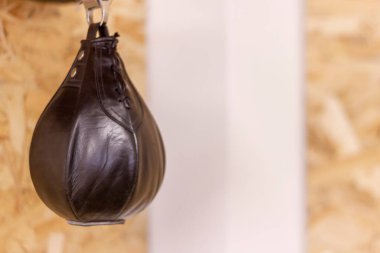 Tahta duvarda asılı duran siyah boks topu.
