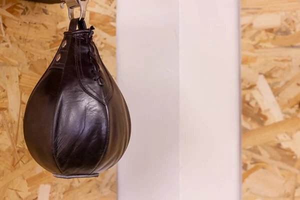black boxing punching ball hanging on the wooden wall