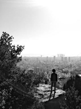 Şehre siyah beyaz bir uçurumdan bakan bir adam.