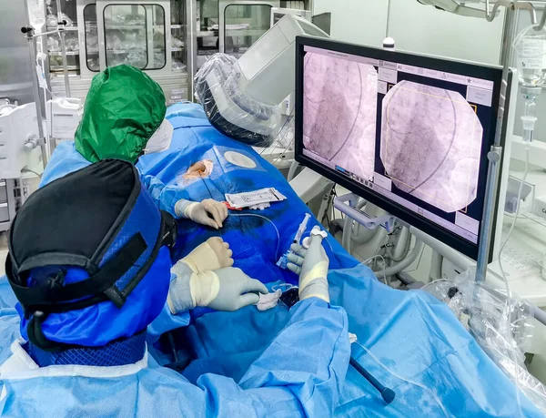 这张照片显示了Covid期间在心脏导管置换术实验室正在进行的紧急冠脉血管成形术 医务人员已全部到位 — 图库照片