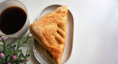 Sıcak sade kahve ve tavuklu turta beyaz bir kabın içinde. Yakınlarda bir buket güzel çiçek vardı..