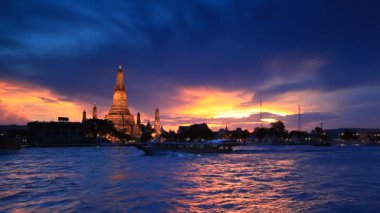 Tekne Chao Phraya Nehri 'nde, Wat Arun' un arka planında gün batımında, Bangkok, Tayland 'da yol alıyordu. Şafak Tapınağı 