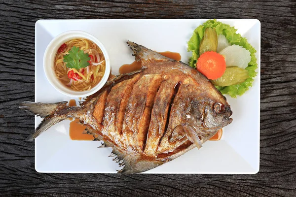 Balık soslu bol yağda kızartılmış Pomfret kırsal bir dokuda yukarıdan izole edilmiş. 