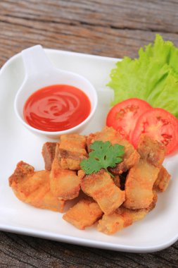 Kızarmış domuz eti, beyaz tabakta balık sosu, marul ve domatesle garnitür 