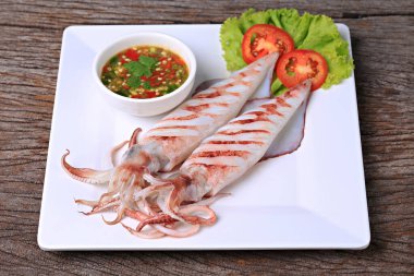 Kömür üzerine ızgara yapılmış büyük kalamar yumurtaları baharatlı deniz ürünleri sosu ve menüde kullanılacak yemek fotoğraflarıyla servis ediliyor. 