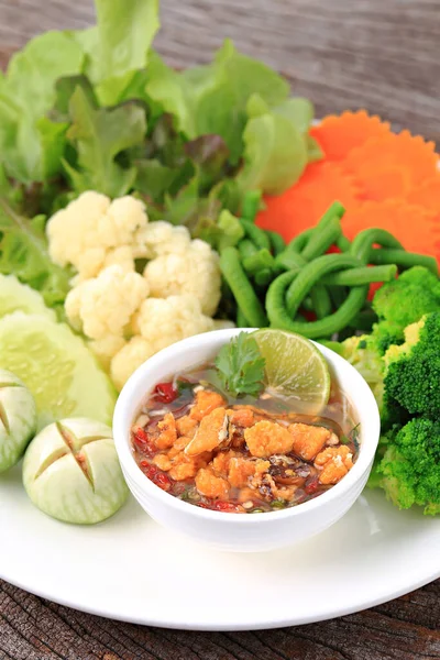 Baharatlı Yengeç Roe Relish Paste ve eski ahşap arka planda taze sebze karışımı. 