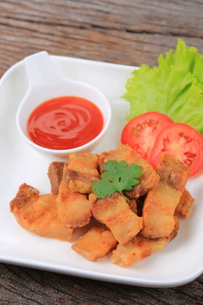 Kızarmış domuz eti, beyaz tabakta balık sosu, marul ve domatesle garnitür 