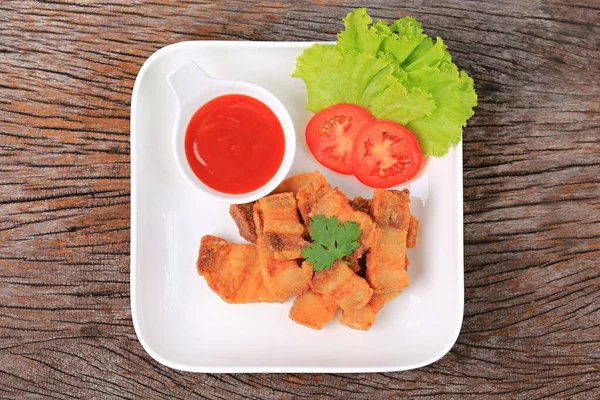 Kızarmış domuz eti, beyaz tabakta balık sosu, marul ve domatesle garnitür 