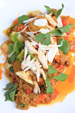 Köri tozu ile karıştırılmış yengeç eti, üstü beyaz tabakta haşlanmış yengeç etiyle süslenir. 