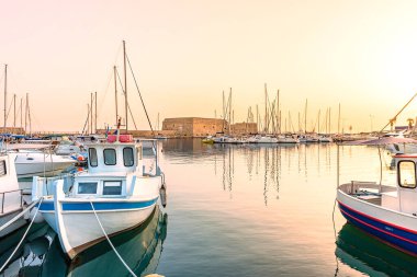 Yunanistan 'ın Girit adasındaki Heraklion şehrinin limanında (Venedik limanı) geleneksel balıkçı teknesi. Arka planda Koulesy kalesinin yeri belirlendi. Gün doğumu zamanı.