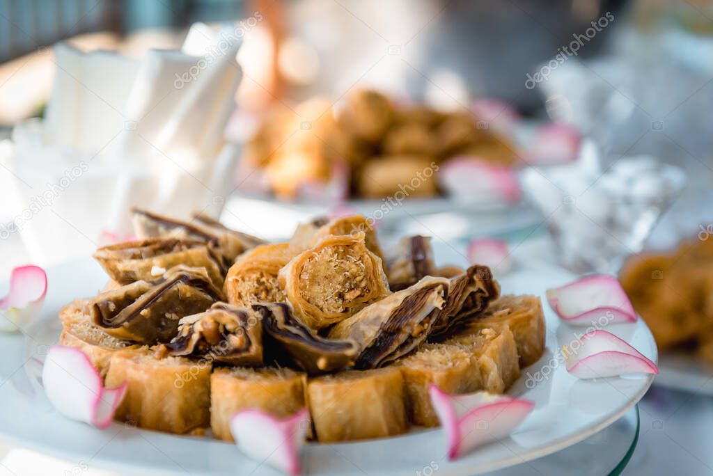 Oriental sweets. Traditional greek dessert Baklava with honey and walnuts on a plate, blurred background.