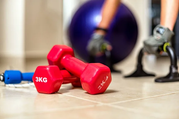 Fitness ball, dumbbells and other sport equipment on the floor of the living room. Home fitness and workout.