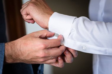 Sağdıç damadın kol düğmelerini takmasına, düğün hazırlıklarına yardım ediyor.