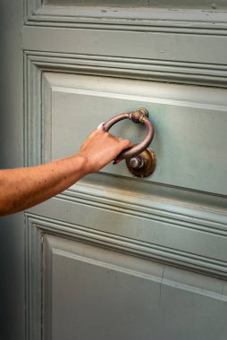 Kadın eli vuruyor ahşap zeytin rengi tahta kapı, evin önünde.