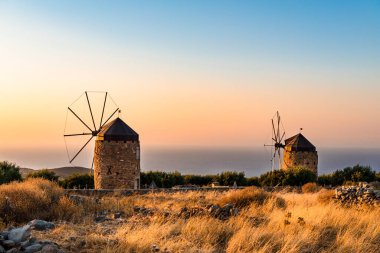Altın saat günbatımında dağlarda iki yel değirmeni