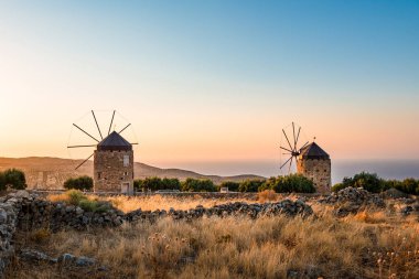 Akdeniz manzarası, gün batımında iki eski yel değirmeniyle