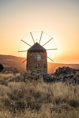 Gün batımında dağ manzarasında yapayalnız yel değirmeni