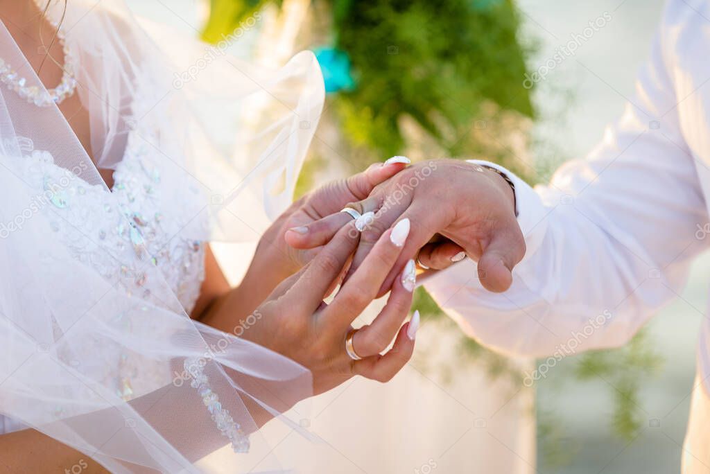 The bride places the ring on the groom's hand. Photo closeup. Wedding details.