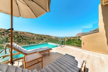 Sonsuz havuzlu, güneşli, manzaralı dağlara ve denize bakan şemsiyeli bir teras. Yaz tatili, dinlenme ve Akdeniz seyahati yaşam tarzı..