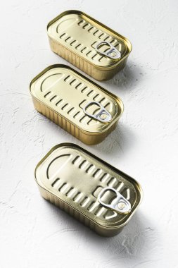 Aynı boyutta kapalı konserve yiyecek, balık, meyve, sebze, et, çorba farklı şekillerde üst görünüm beyaz desenli arka plan görüntüsü.