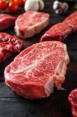 Alternatif siyah angus, eski ahşap masa manzaralı kasaplıkta kesilen diğer kesiklerin hemen önünde üst bıçak bifteğini kesiyor..