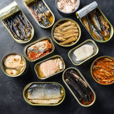 Teneke kutu Saury, uskumru, ispinoz, sardalya, sardalya, kalamar, kalamar, ton balığı. Siyah tahta kaplama arkaplan üstü kare görünümü üzerine açılıp kapanır..