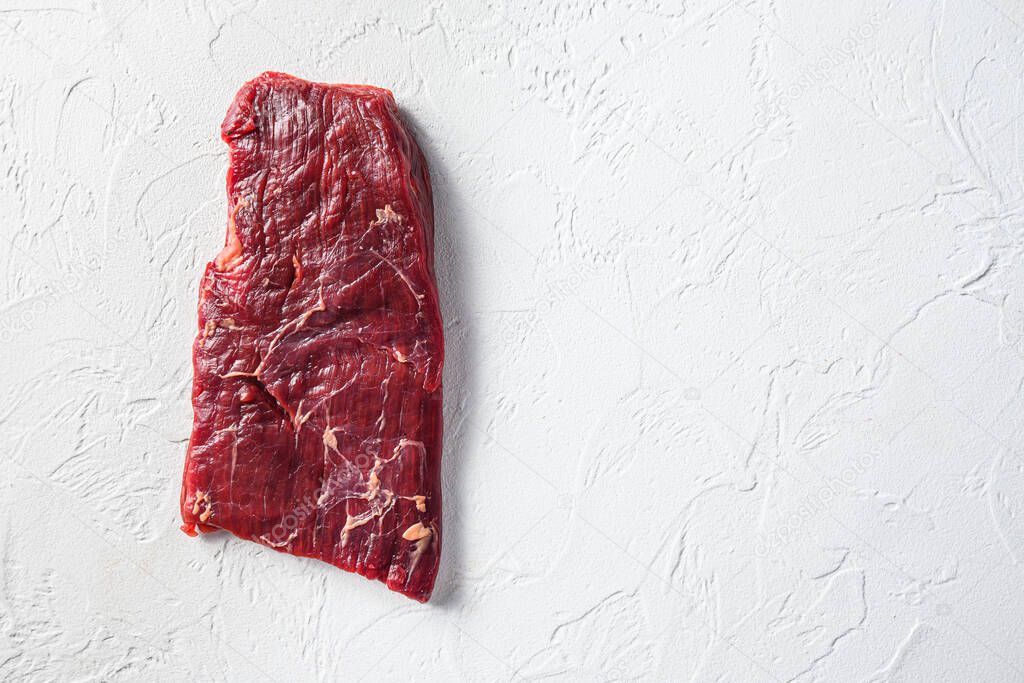 Raw skirt or flank steak,on a white stone background top view space for text
