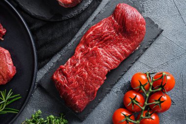 Çiğ ekmek, siyah bir tabakta siyah angus organik bifteği baharatlı taş levha, yeşil çimento arka plan. Üst görünüm kapat