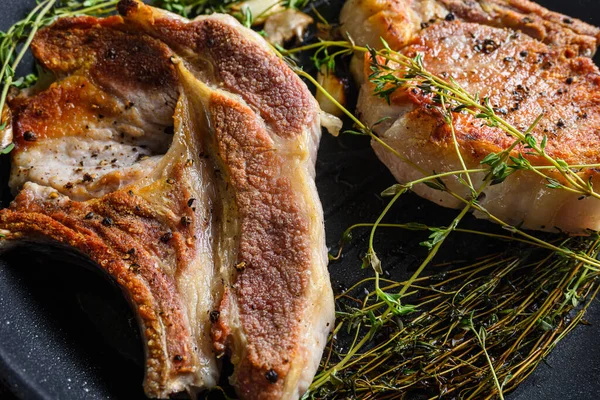 Izgara organik domuz bifteği ve kemikli otlar ızgarada kızartılmış tavada sıcak duman ve sıcak yağla sadece ateşten, en üstteki pişirme kemiğinde baharatlı, taşralı metal arka planda yakın çekim